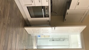 A modern kitchen with white cabinets, a stainless steel range hood, and a built-in oven. - SunWine Bed & Breakfast (Taranto)