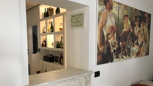 A room with a white fireplace, a painting on the wall, and a shelf with various bottles. - SunWine Bed & Breakfast (Taranto)