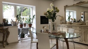 A dining area with a glass table and chairs, surrounded by potted plants and a decorative mirror. - SunWine Bed & Breakfast (Taranto)