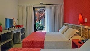 Camera d'albergo con un letto, una scrivania con un computer, una lampada e vista su uno spazio esterno.