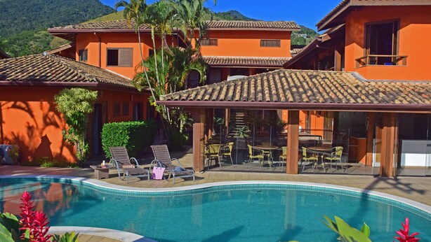 Un resort con piscina, area salotto esterna e montagne sullo sfondo.