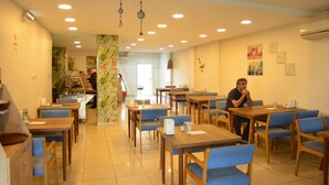 Un restaurante con mesas de madera y sillas azules, una barra con productos alimenticios y una persona sentada en una mesa.