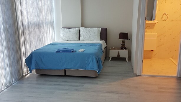 Un dormitorio con una cama, una mesita de noche y un baño visible a través de una puerta abierta.