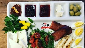 Una bandeja con diversos alimentos, como tomates, hierbas, queso y huevos cocidos.