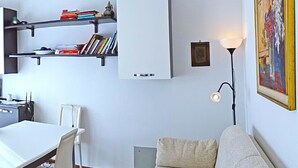A compact living space with a dining area, a sofa, a bookshelf, and a painting on the wall. - La Quiete 17 Holideal (Tremosine)