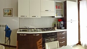 A compact kitchen with white cabinets, a gas stove, a sink, and a coffee maker. - La Quiete 17 Holideal (Tremosine)