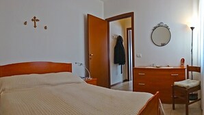 A bedroom with a large bed, a wooden dresser, a chair, a mirror, and a door leading to another room. - La Quiete 17 Holideal (Tremosine)