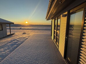 A building with a glass door and a view of the sunset over a snowy landscape. - Farmer's Guest House (Rangárþing ytra)