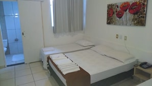 Quarto com cama, mesa de cabeceira, telefone e um quadro na parede.