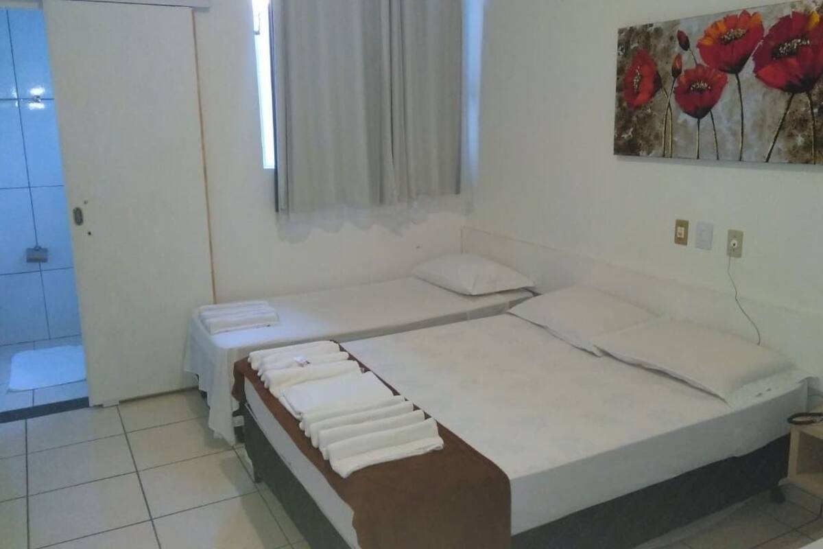A bedroom with a bed, a bedside table, a telephone, and a painting on the wall.