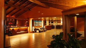 Een hotel lobby met een receptiebalie, een zithoek en een groot raam.