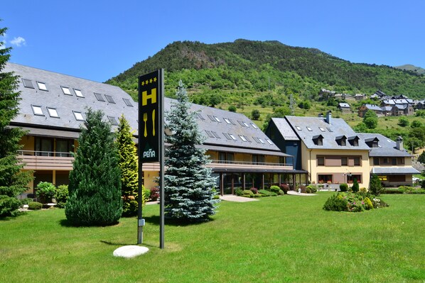 A hotel with a modern design, featuring multiple floors and a prominent sign with a mountain view in the background. - Hotel & Restaurante Peña (Vielha e Mijaran)