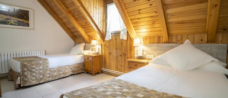 Un dormitorio acogedor en el ático con dos camas, vigas de madera, una ventana con cortinas y un cuadro en la pared.