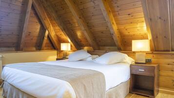 A wooden ceiling with exposed beams, a bed with white linens, two bedside lamps, and a nightstand with a clock.