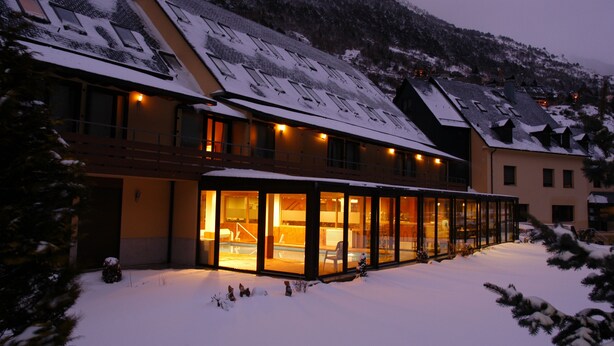 Een gebouw bedekt met sneeuw, met een glazen patio en een zwembad.