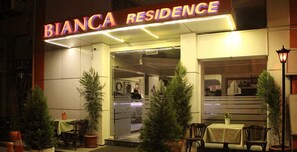 The exterior of Bianca Residence with a neon sign, outdoor seating area, and potted plants. - Bianca Residence (Izmir)