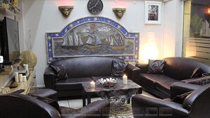 Ein Wohnzimmer mit einem dunkelbraunen Ledersofa, einem kleinen Couchtisch mit Kerzen und einem dekorativen Wandbild darüber.