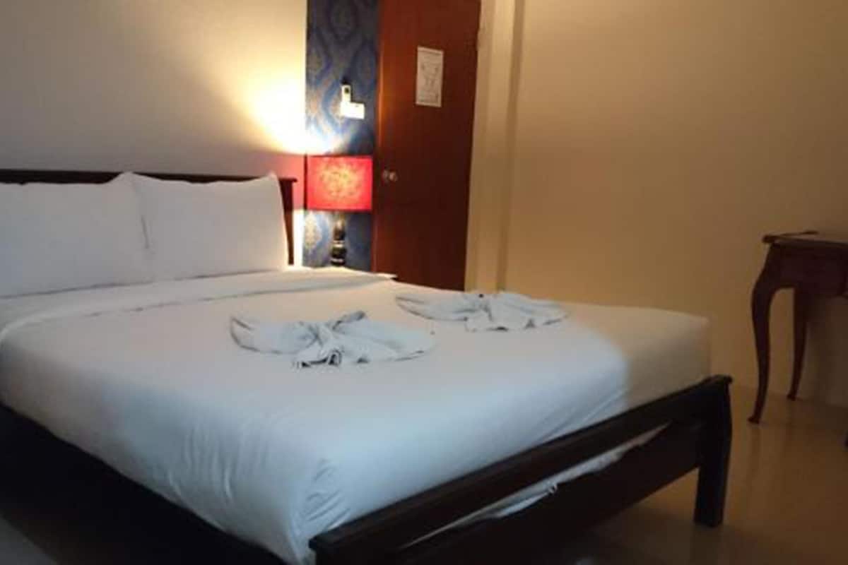 Una cama bien hecha con sábanas y toallas blancas dispuestas sobre ella.