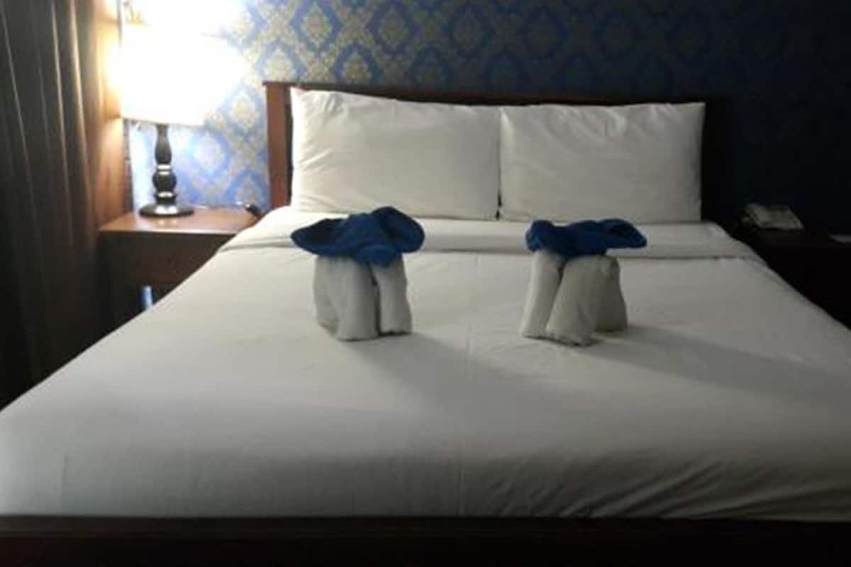 Una cama bien hecha con sábanas blancas y dos toallas dobladas en el centro.