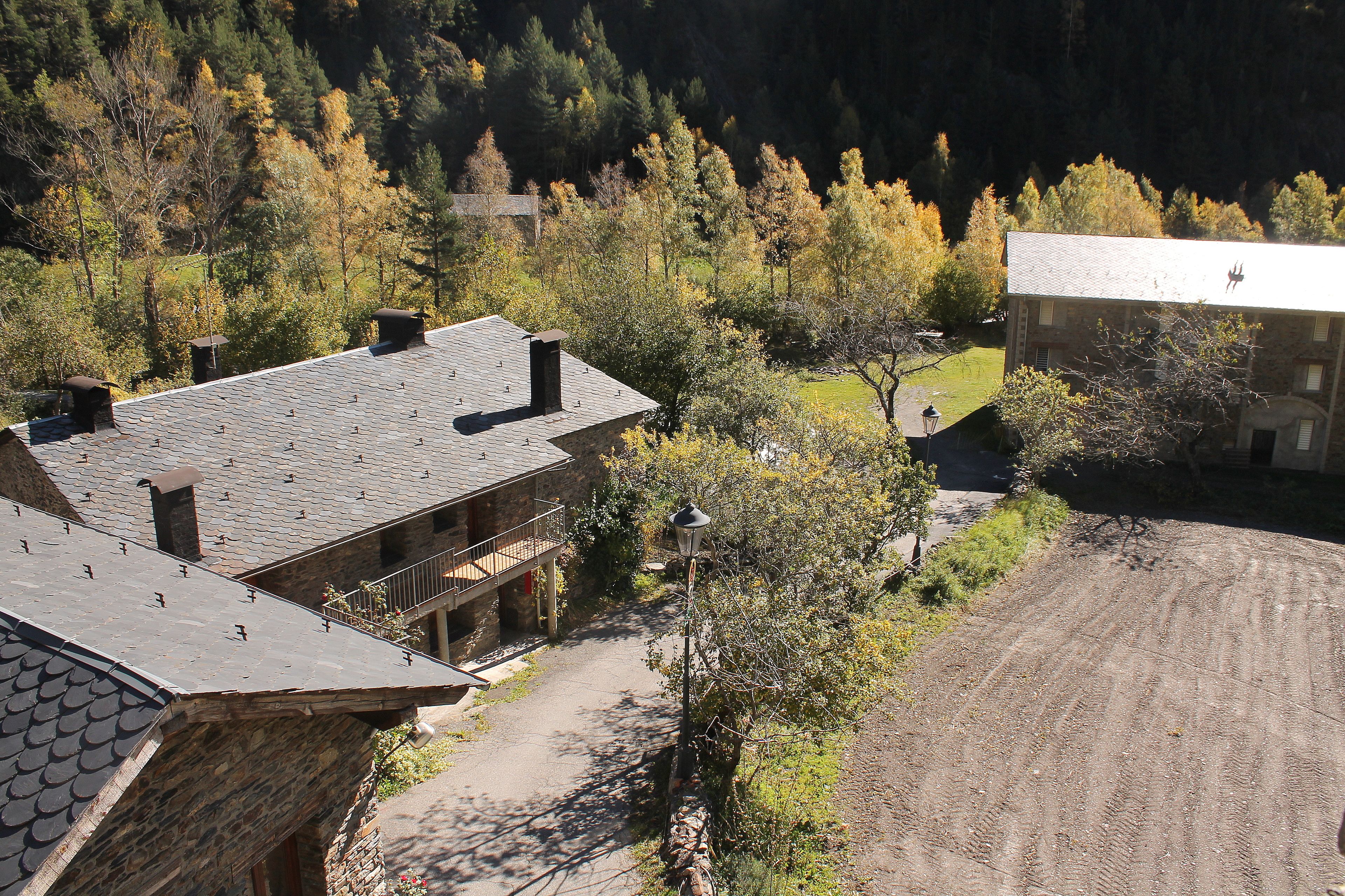 A stone building with a sloped roof, a paved driveway, and a dirt path.