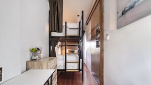 A narrow hallway with a bunk bed, a wooden desk, a white dresser, and a refrigerator. - OYO 685 Am Bed Hostel (Bangkok)