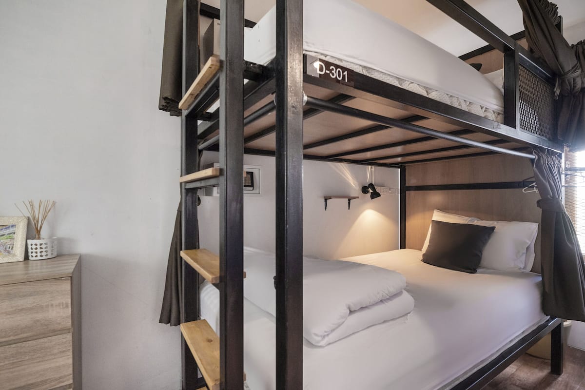 Ein Stockbett mit dem Schild "P-301" in einem Zimmer mit einem Holzschrank und einem Bilderrahmen.