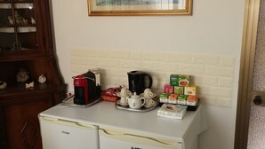 A compact kitchen area with a Haier refrigerator, a coffee maker, and a tea set on the counter. - Privacy & Relax in Sardegna (Alghero)