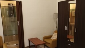 A bedroom with a bed, a wooden table, a sofa, a wardrobe, and a glass shower enclosure. - Privacy & Relax in Sardegna (Alghero)