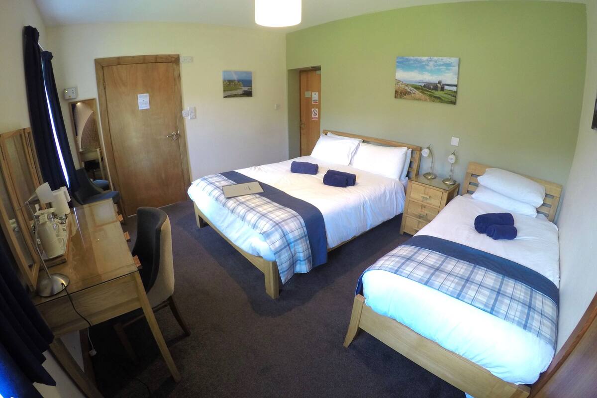 A hotel room with two beds, a desk, and a chair.
