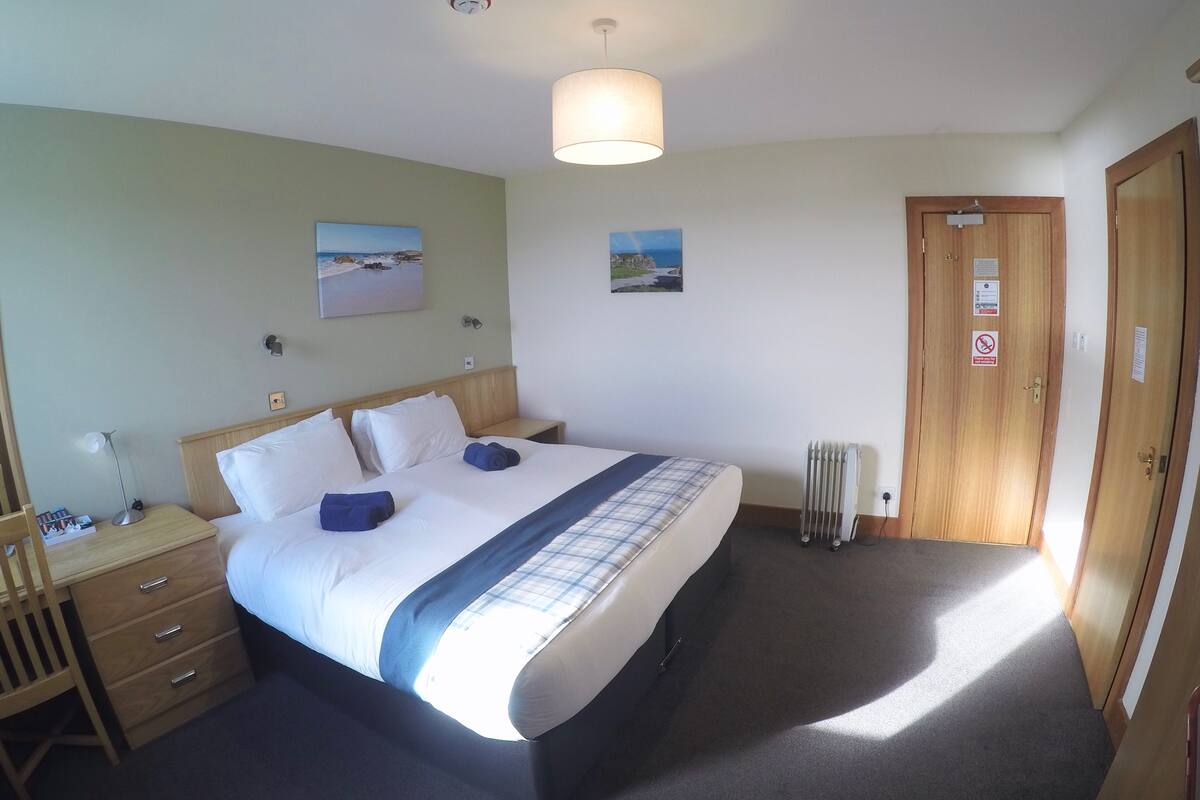 A neatly arranged bedroom with a bed, bedside table, lamp, and a radiator.