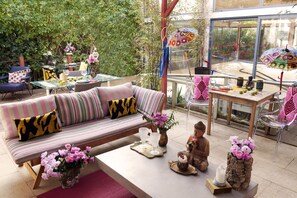 A cozy outdoor seating area with a striped sofa, a dining table, and a statue. - Lucky's Guest House (Cascais)