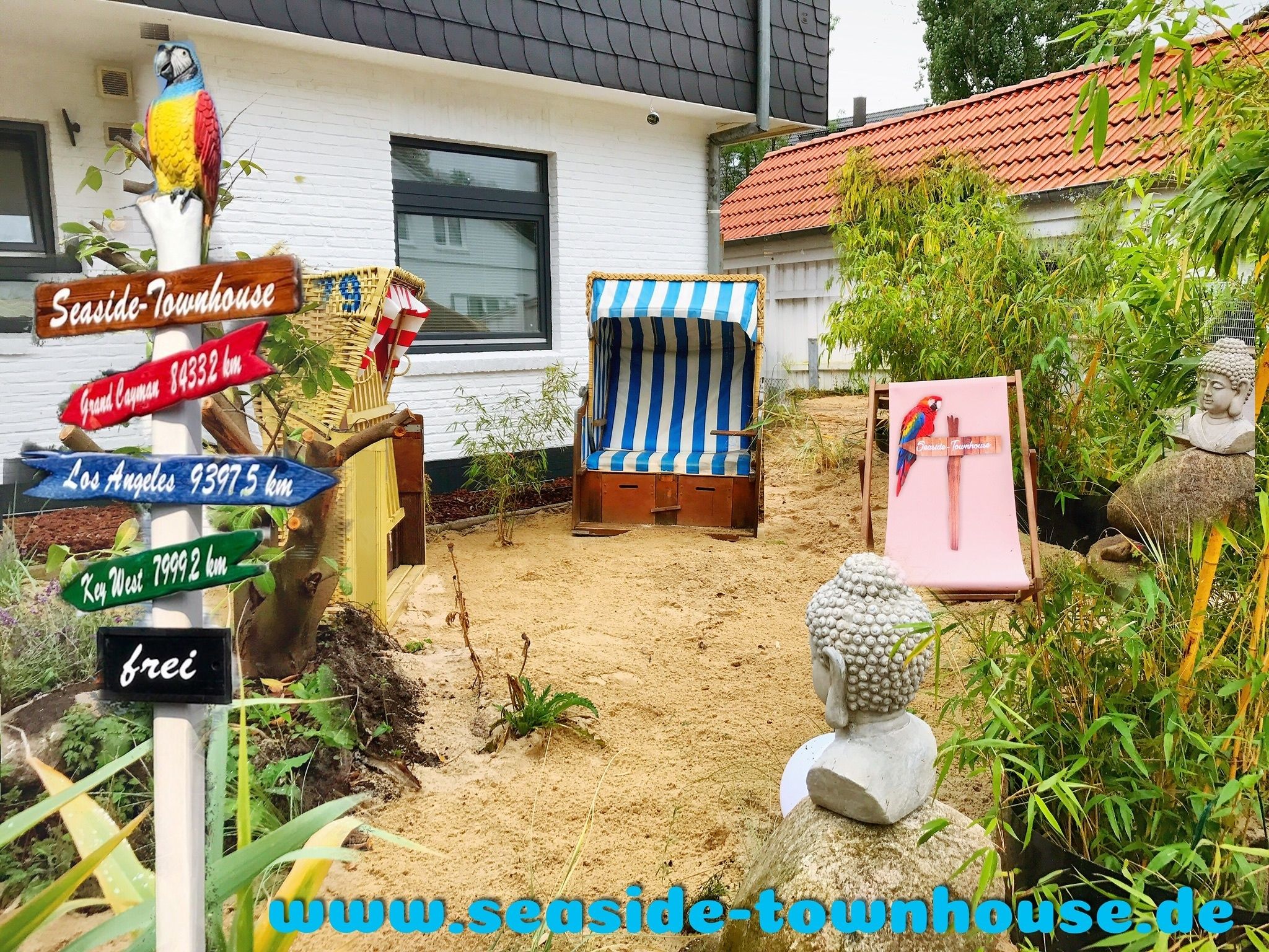 Une maison de plage avec un panneau indiquant les distances vers Grand Cayman, Los Angeles et Key West.