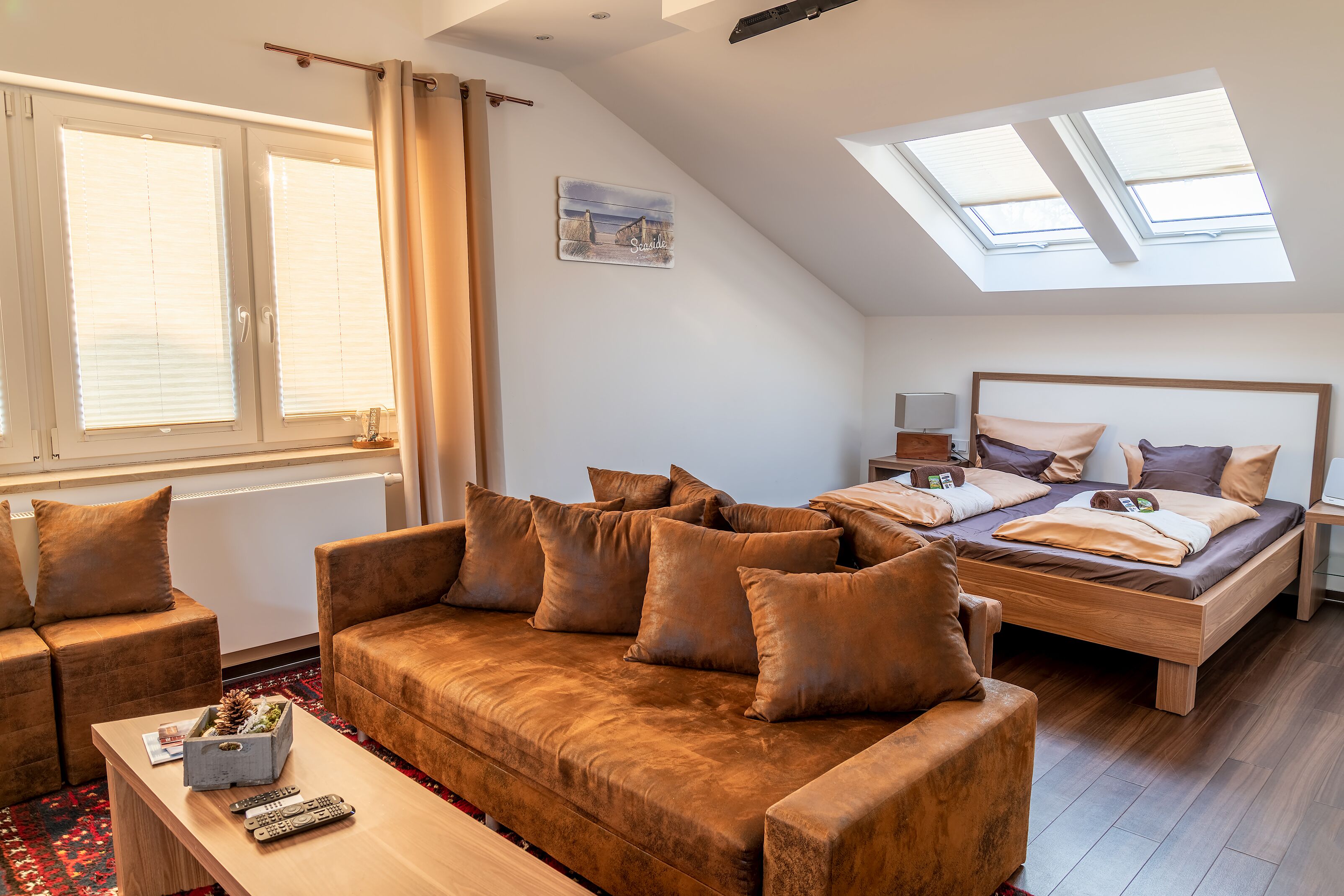 A cozy room with a brown sofa, a wooden bed, and a skylight.