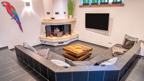 Een moderne woonkamer met een modulaire bank, een houten salontafel en een open haard.