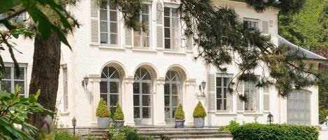 Un edificio blanco con ventanas de arco y un césped cuidado.