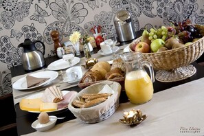 A breakfast table with various food items, a coffee pot, and a fruit basket. - Hotel Fleur de Lys (Zedelgem)