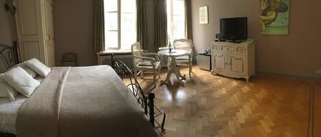 A hotel room with a bed, a small table with chairs, a television, and a cabinet.