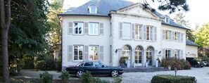A two-story house with a driveway and a parked car. - Hotel Fleur de Lys (Zedelgem)