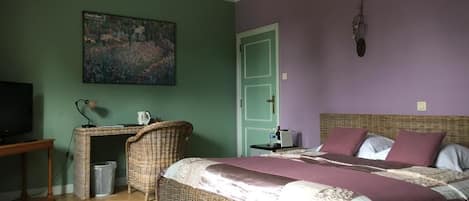 A bedroom with a large bed, a desk, a chair, a television, and a painting on the wall.