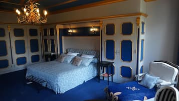 Ein Schlafzimmer mit einem großen Bett, Nachttischen, einem Sessel und einer Kronleuchter.