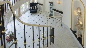 A grand interior with a spiral staircase, a chandelier, and a seating area with a statue. - Hotel Fleur de Lys (Zedelgem)