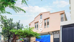 Un edificio con il cartello "OYO" sulla facciata, circondato da alberi e un telo blu.