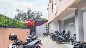 Un’area di parcheggio con diverse motociclette e scooter, un cartello con la scritta 'OYO' e un edificio con la segnaletica 'OYO'.