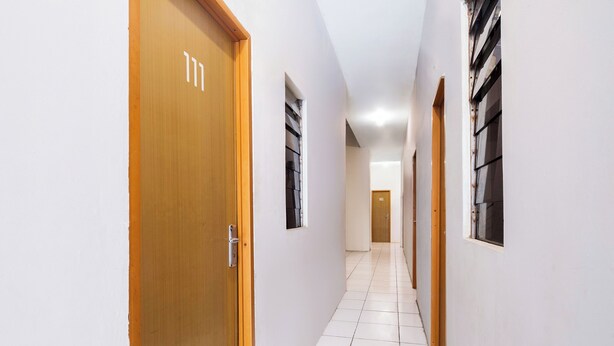 Un corridoio con porte e finestre in legno, che conduce a una stanza con la scritta "MB".