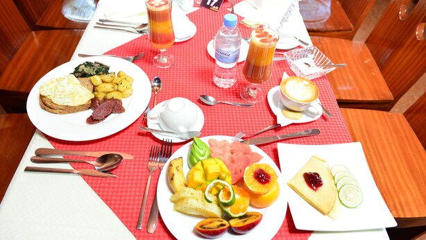 Una mesa de desayuno con platos de comida, bebidas y cubiertos.