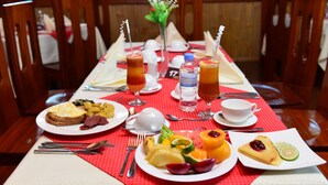 Une table dressée pour le petit-déjeuner, avec des assiettes de nourriture, des boissons et des couverts.