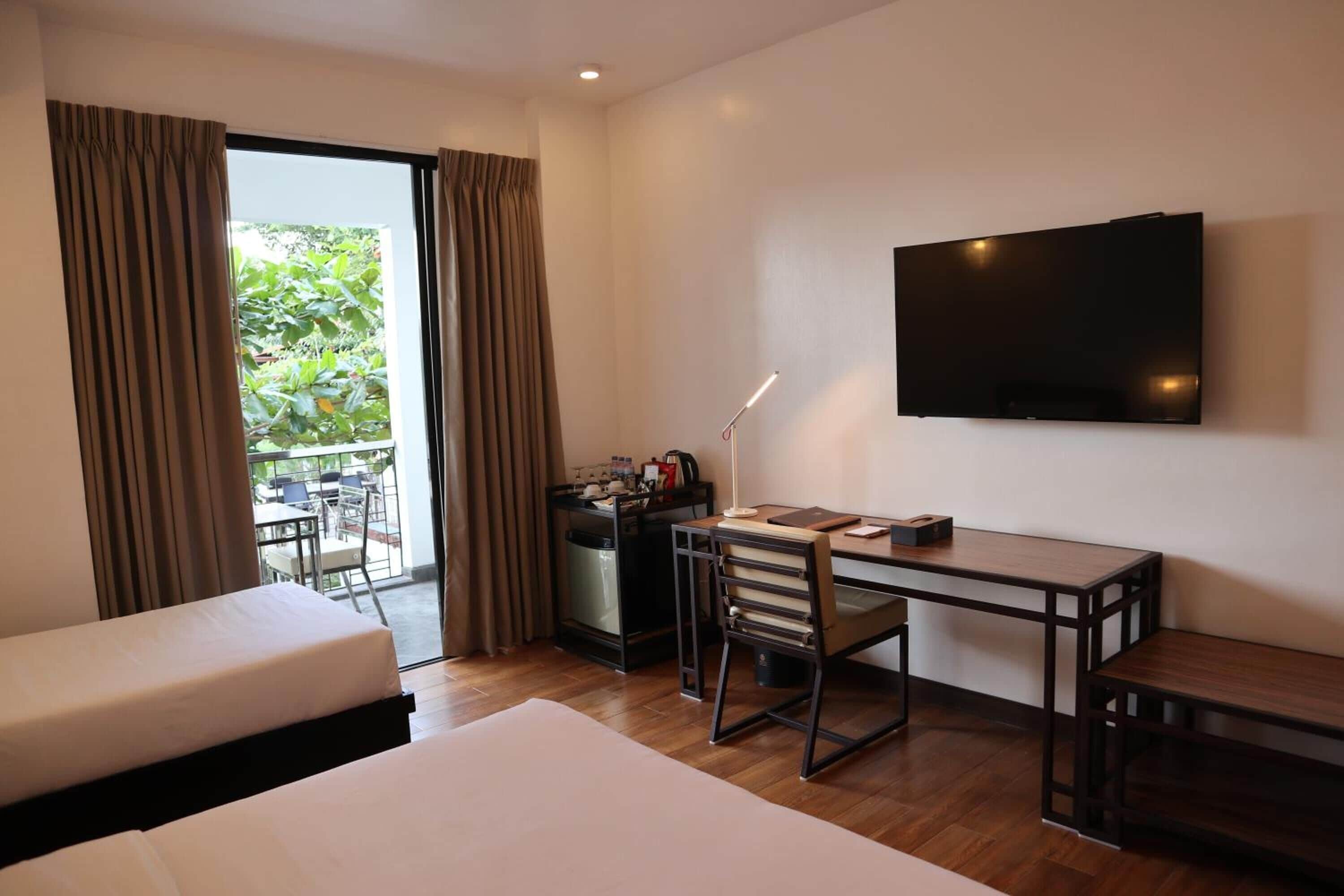 A hotel room with a bed, a desk, a chair, a television, and a view of the outdoors.