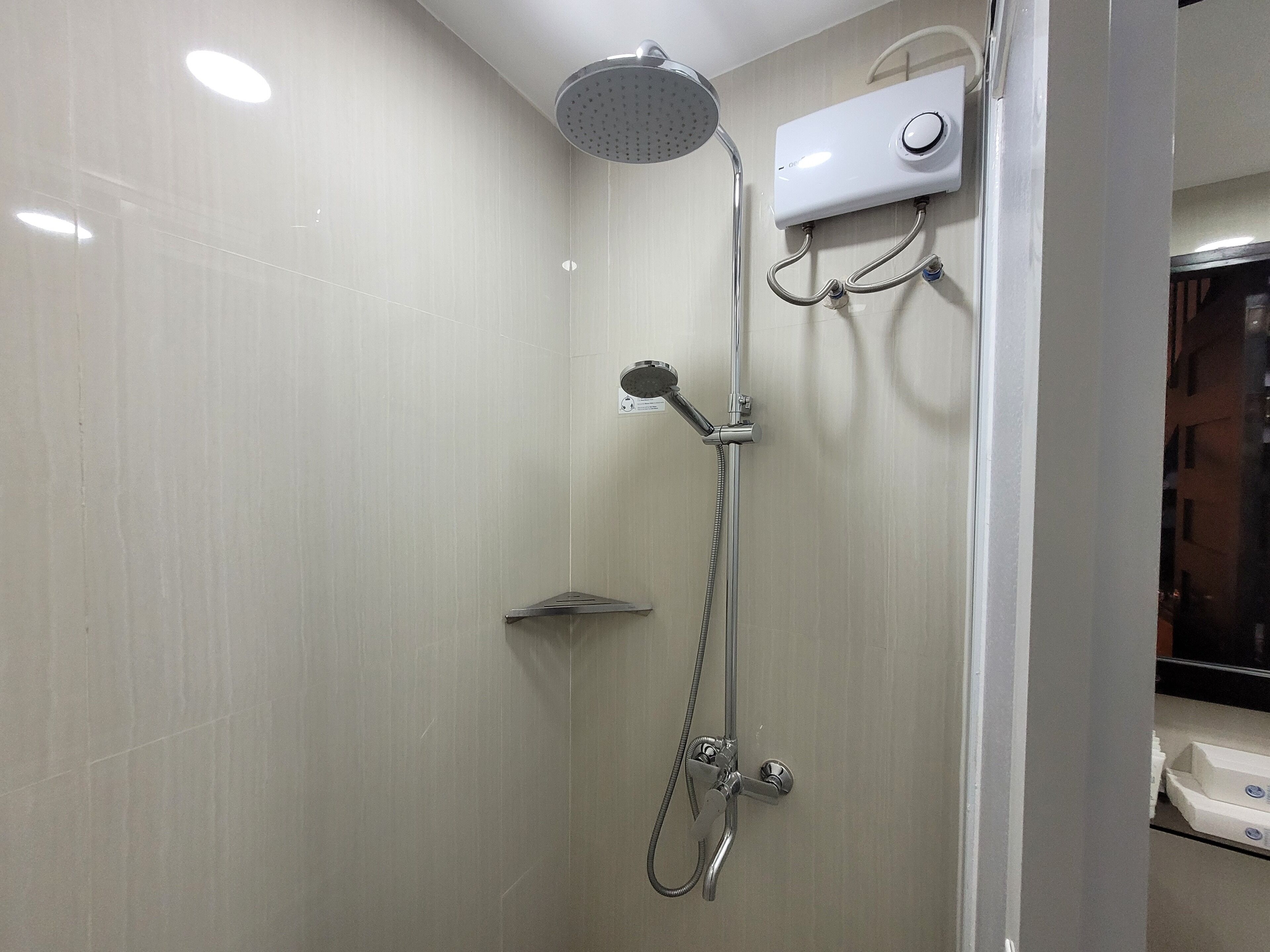 A modern shower with a handheld showerhead, a fixed showerhead, and a control panel.