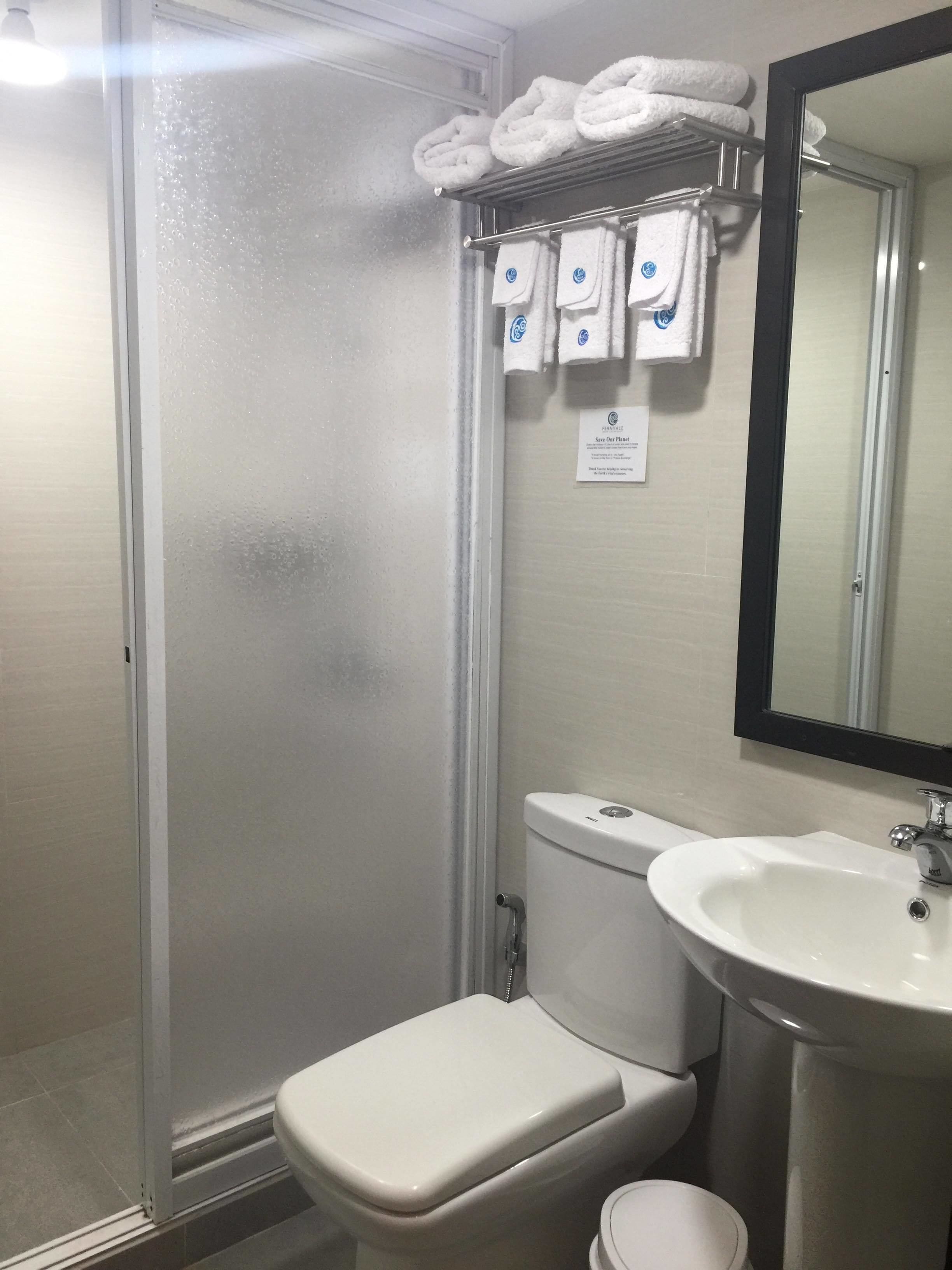 A bathroom with a toilet, sink, and a towel rack with towels.