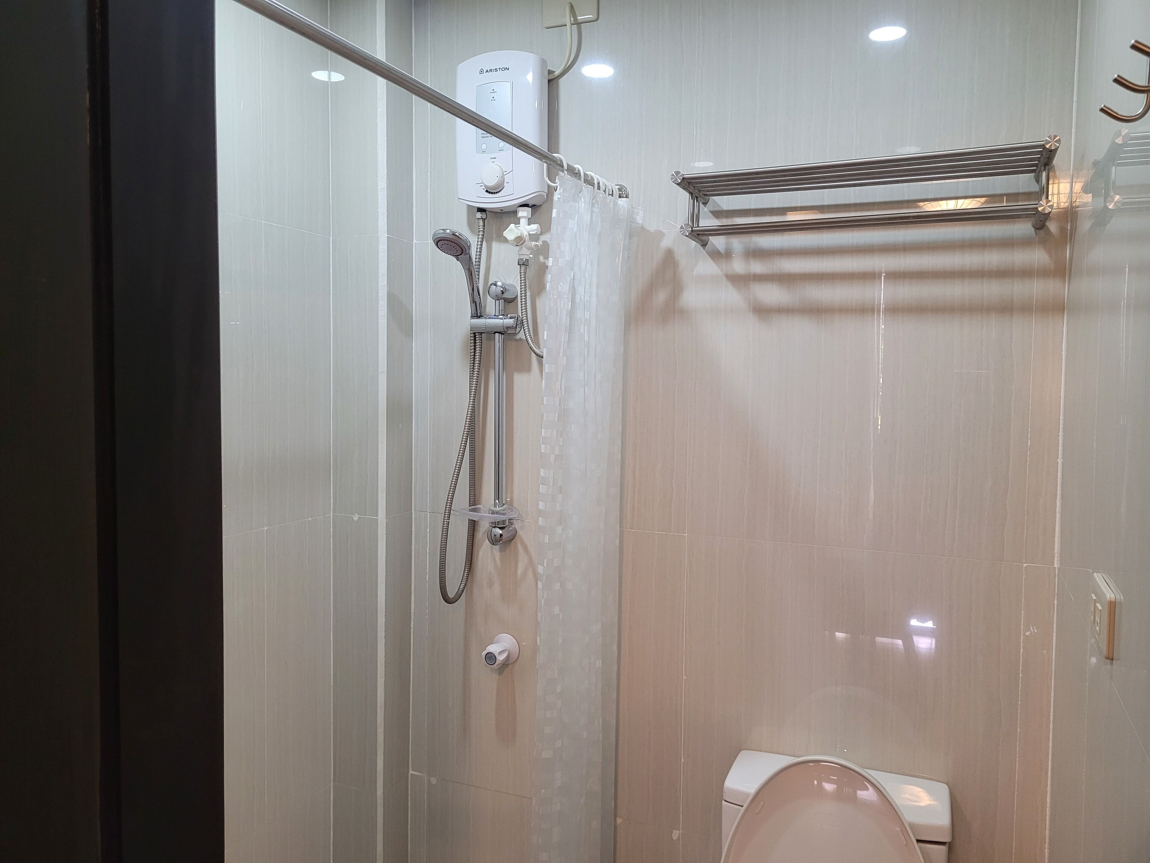Un baño moderno con cabina de ducha de vidrio, un inodoro y un perchero para toallas.